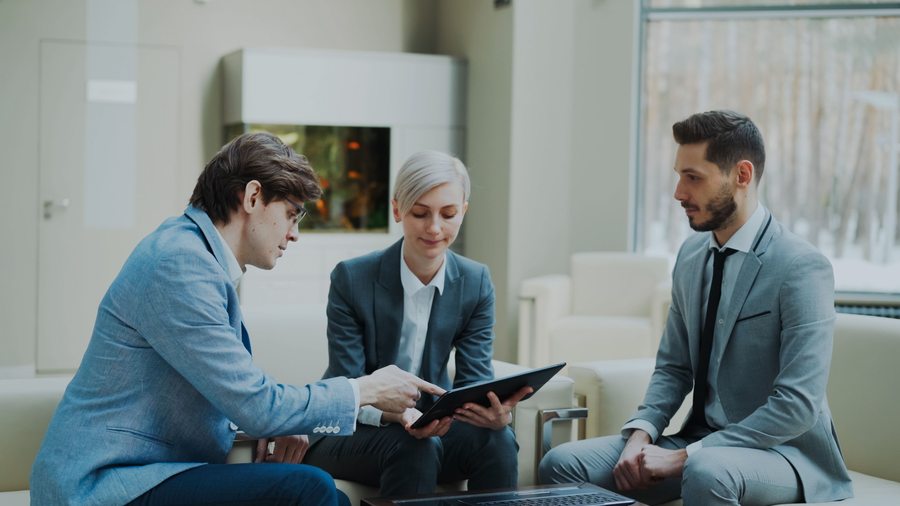 Advisory meeting with three consultants reviewing a tablet